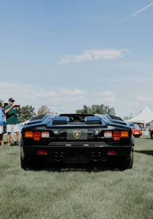 people looking at an older sports car on display