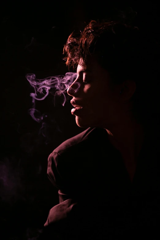 a young woman smoking in the dark with her eyes closed