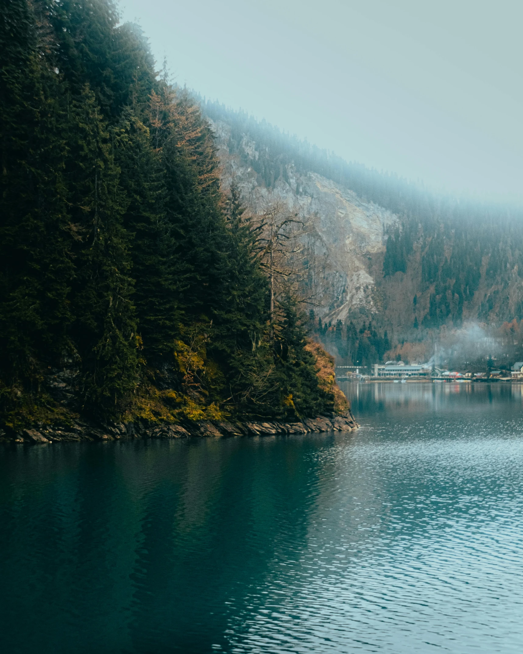 the mountain next to the water has a building near by