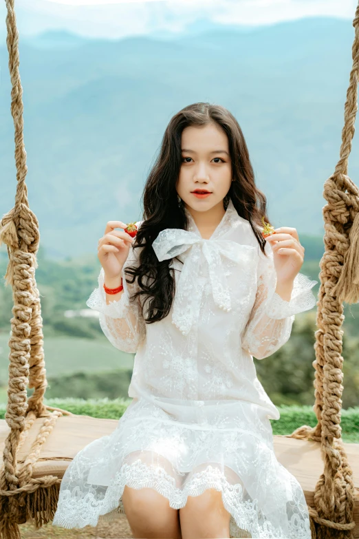 a girl sitting in a swing chair holding a pair of scissors