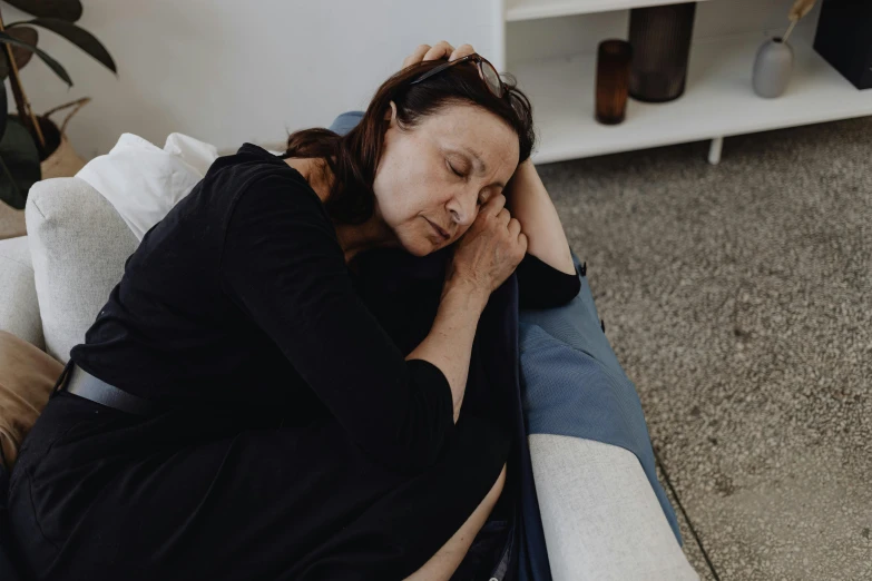 a woman is sleeping on a couch near a coffee table