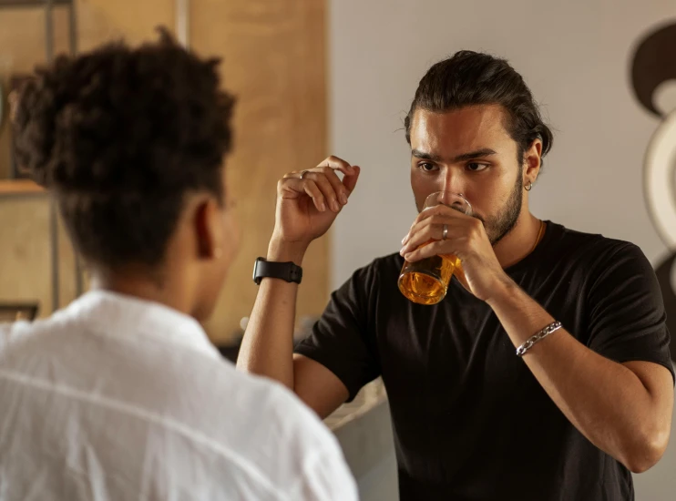 a man sitting at a table drinking a glass of beer