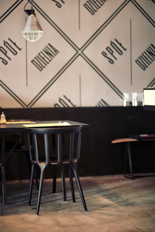 two chairs, table, and a light are in front of a large wall sign