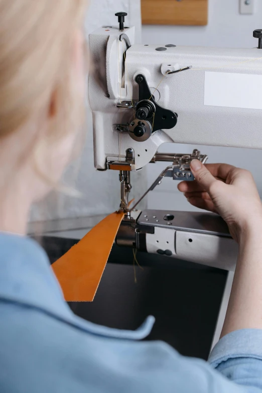 a woman wearing a blue blouse using a sewing machine