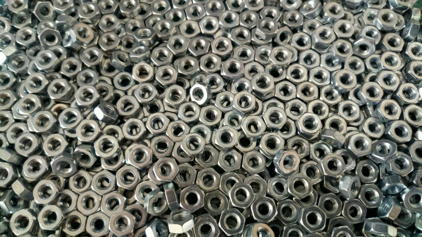 a pile of assorted metal nuts with holes in them