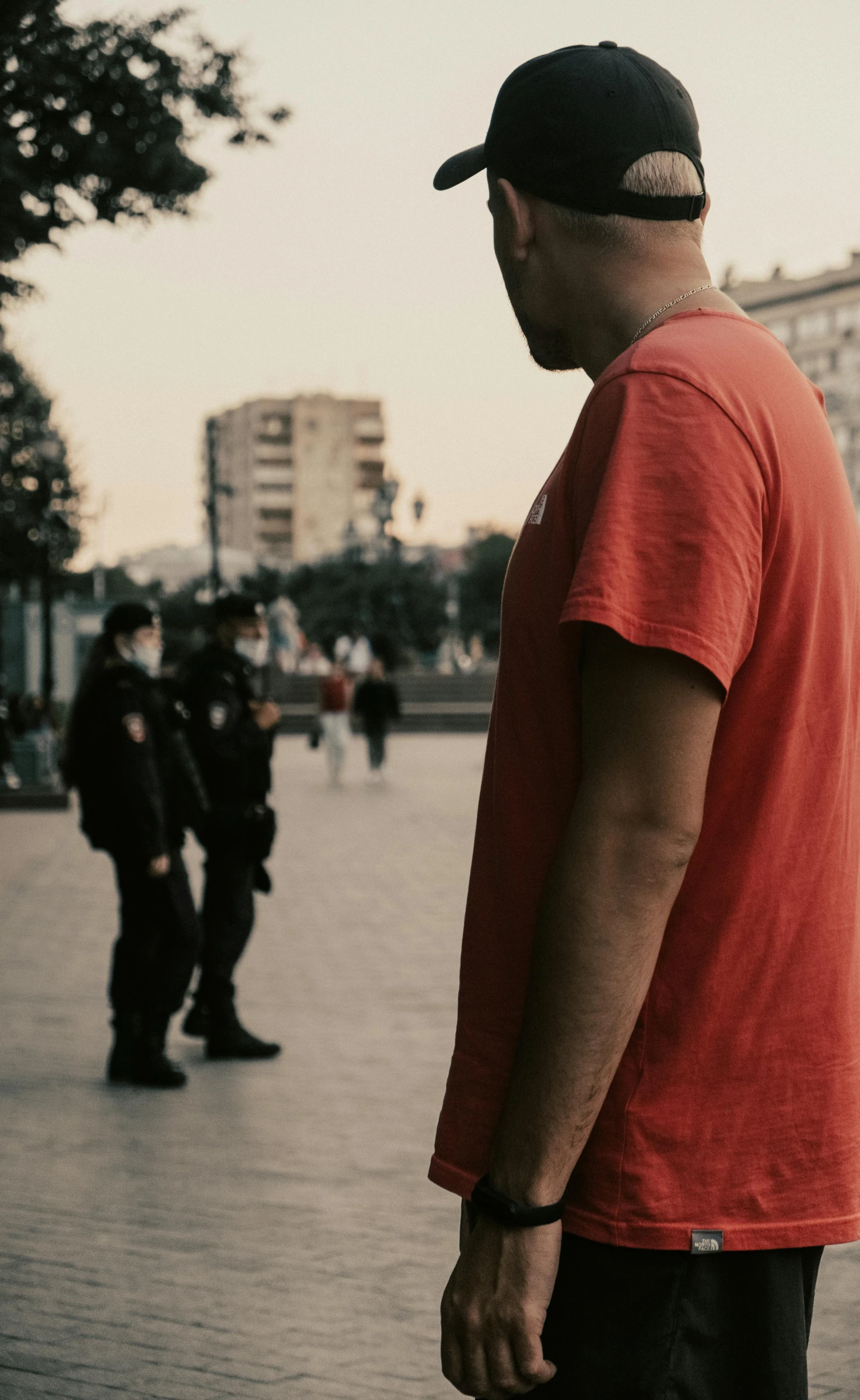 a man wearing a red shirt standing near other people