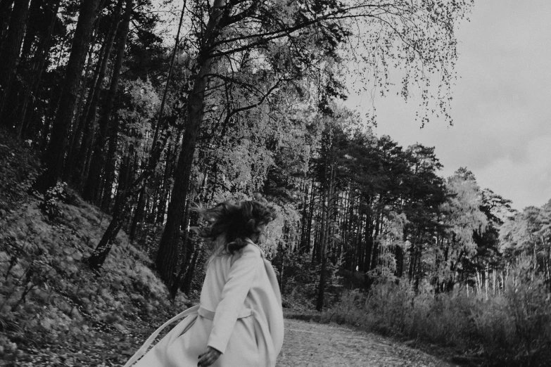 a woman walking through a forest with a blanket on her