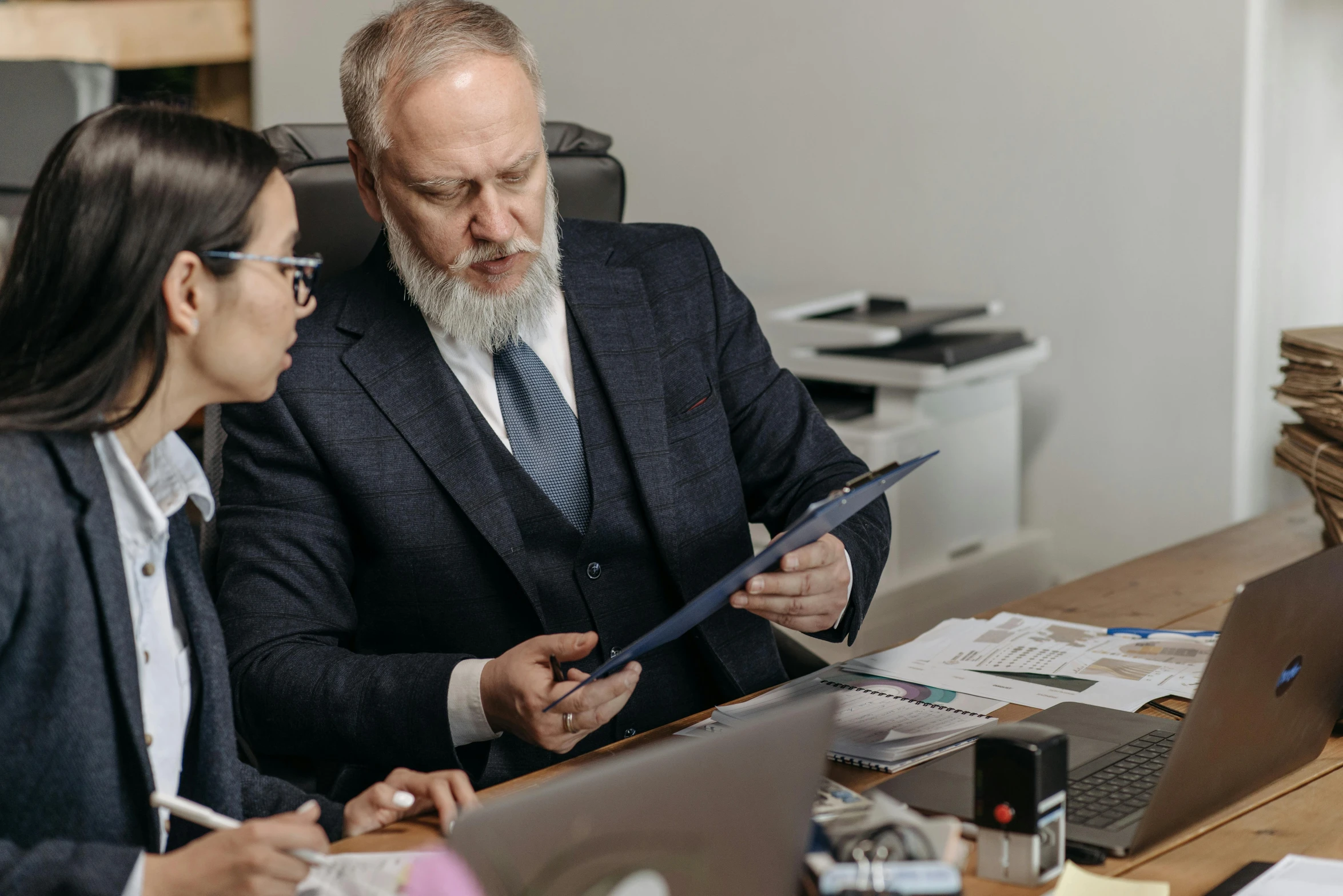 two people in business attire sitting together at a desk