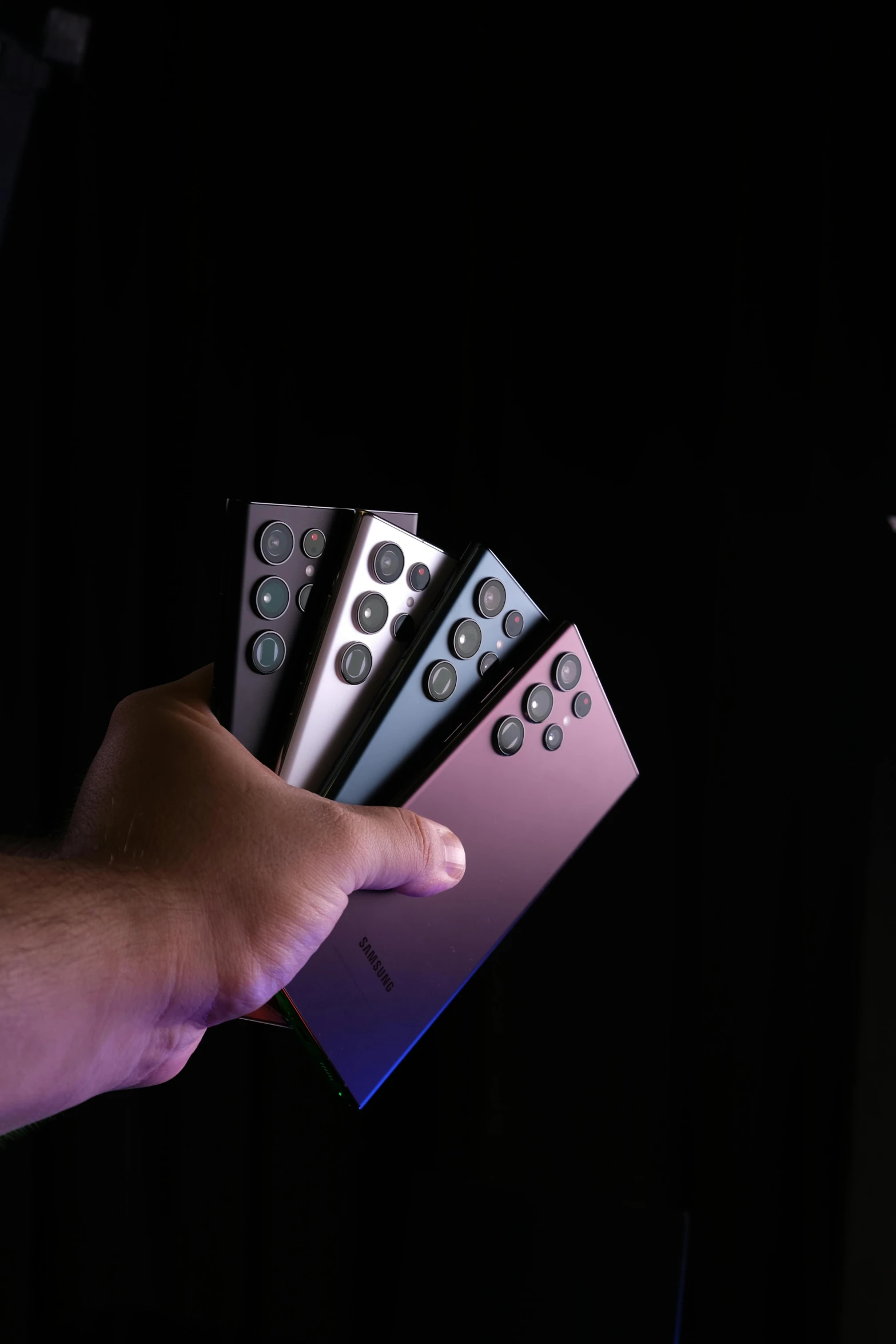 a hand is holding four electronic controls for a projector