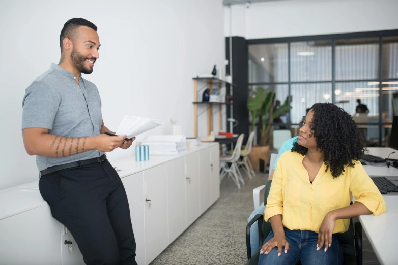 a man smiling while holding papers in front of a woman