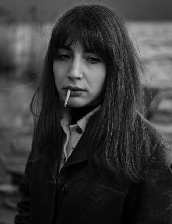 a woman with a cigarette standing by the water