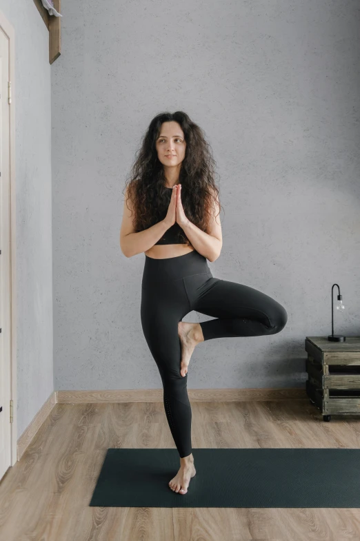 a woman standing in a lotus pose on her yoga mat