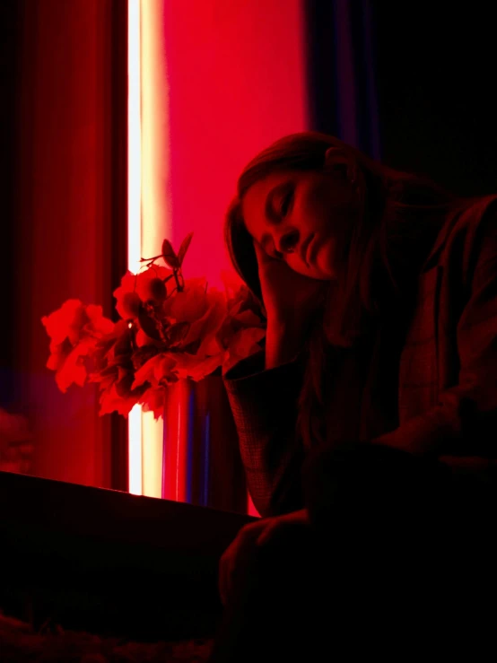 a woman sitting in a dark room with flowers in her hand