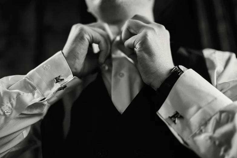 the hands of a man straightening his collar