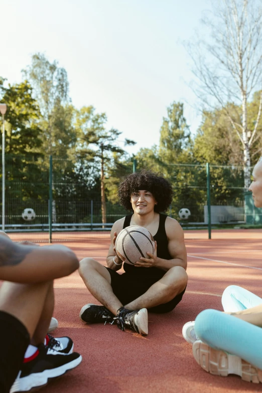 there are two girls sitting on the ground holding basketballs