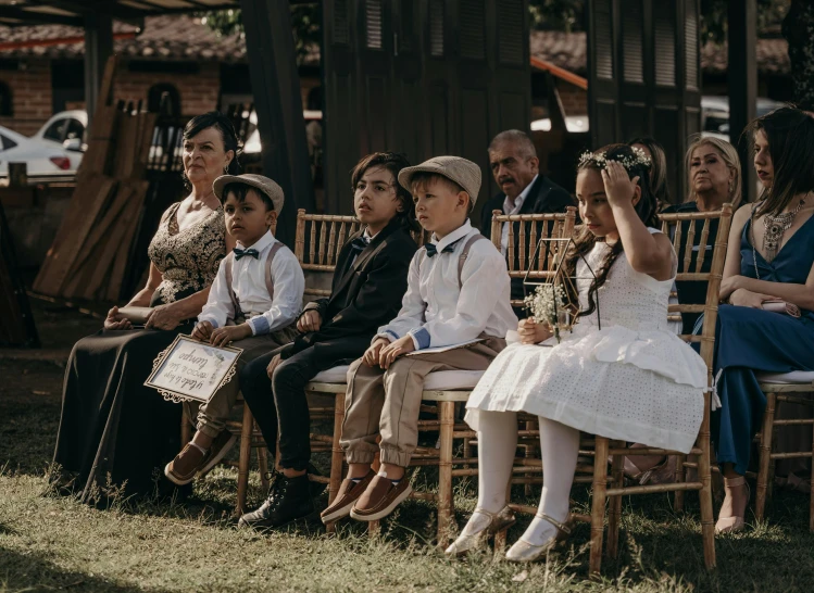 a group of children sitting on chairs and some adults