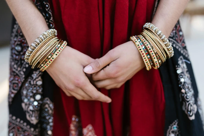 a woman in a red dress holding two large gold banges