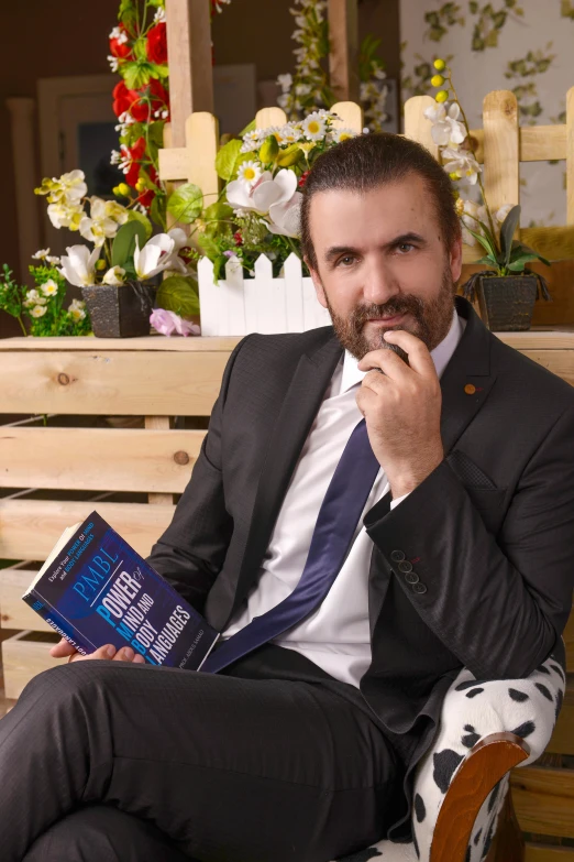 a man with beard sitting on a bench holding a book