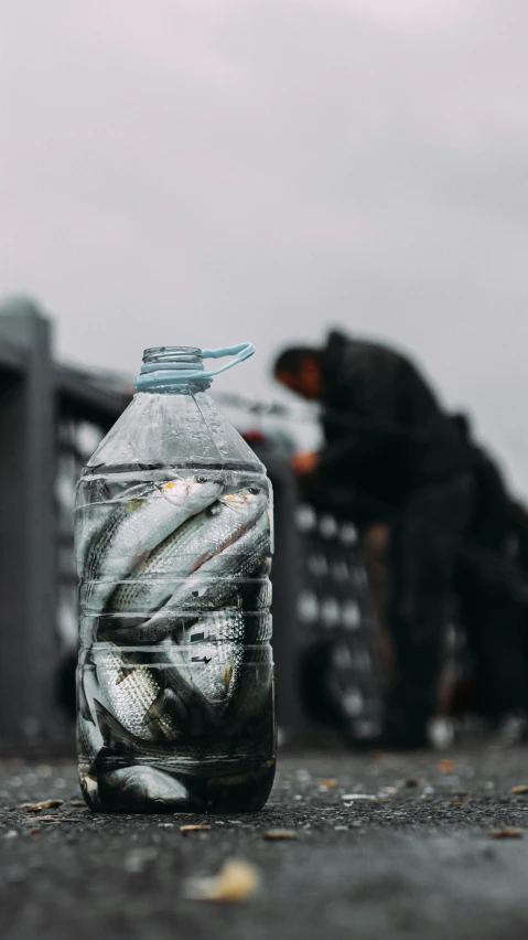 a man sitting on the ground next to a jar full of liquid