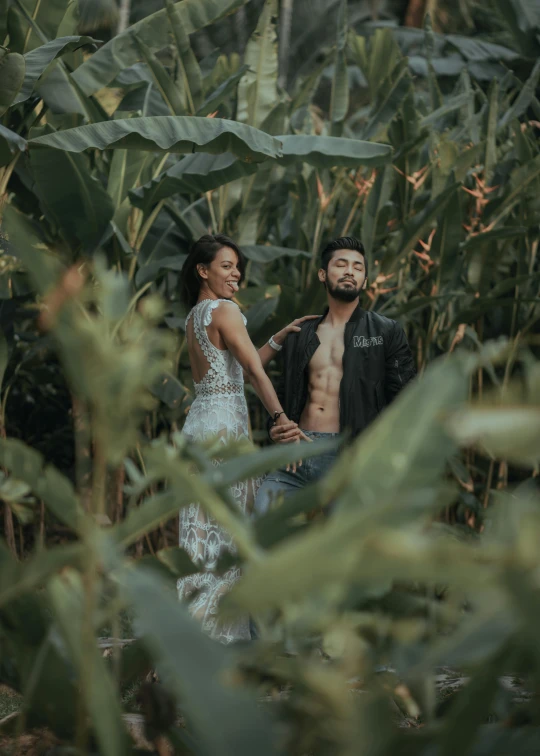 the young couple walks among large green leaves