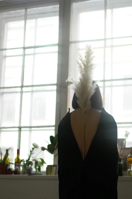 back view of mannequin holding a dress with feathers on it