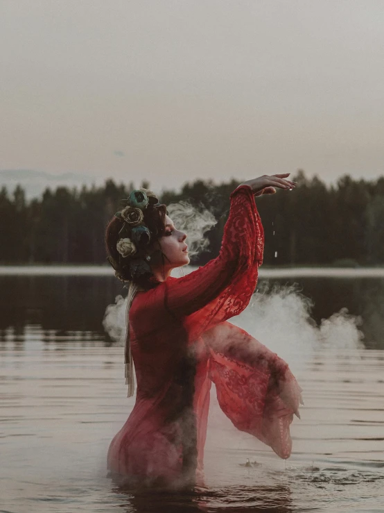 an asian woman in a red dress is dancing in the water