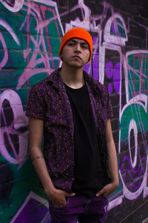 a man leaning against a wall, in front of graffiti