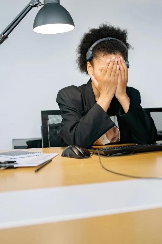 woman covering her face at her computer at work