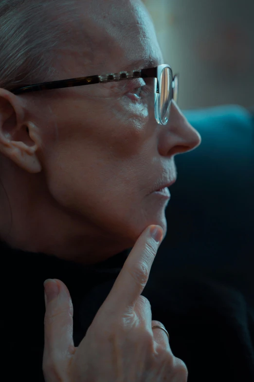 a woman wearing glasses holding her chin under her index finger