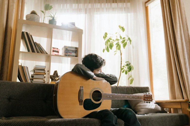 man sitting on couch playing the guitar in front of him