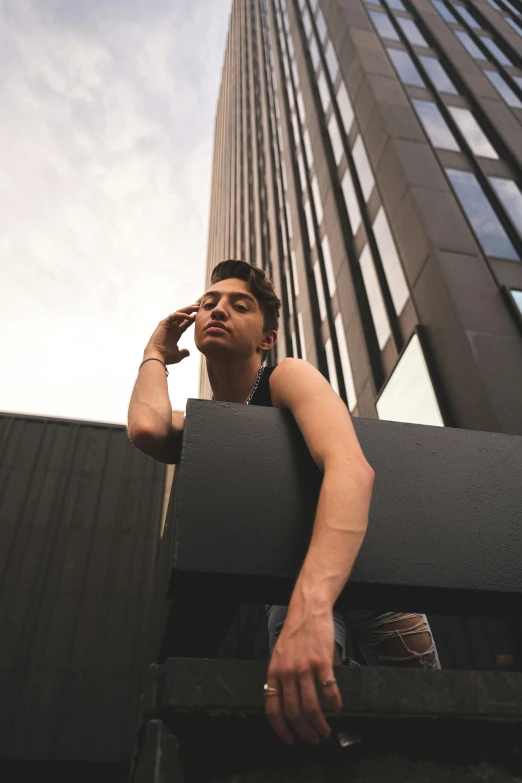 a man in a bikini top leans up against the ledge of a building