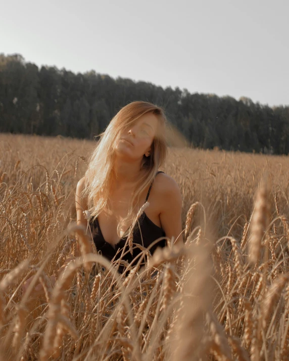 the blonde woman stands in the middle of a large wheat field