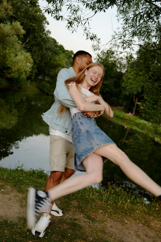 a man and woman dancing next to water on a riverbank