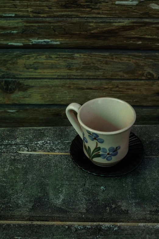 a white coffee cup with blue flowers on a black saucer