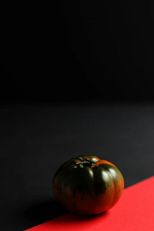 a large green tomato on a red surface