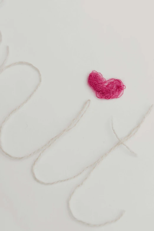 the word love spelled with pink yarn on top of string