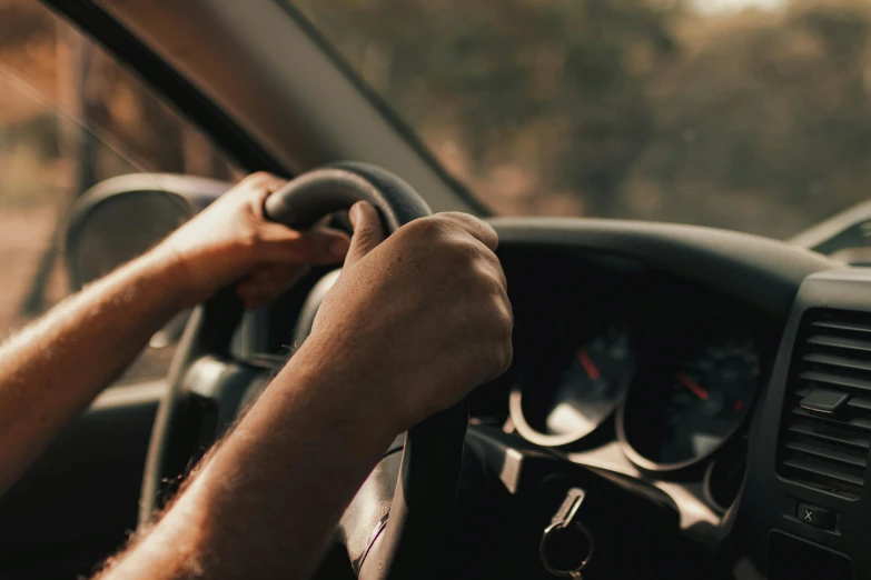 driver hands on steering wheel, holding on to dash board, while another drives