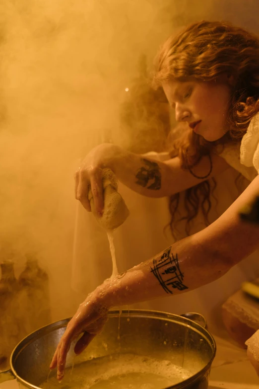 woman cooking in a large pan on the stove with steam behind her