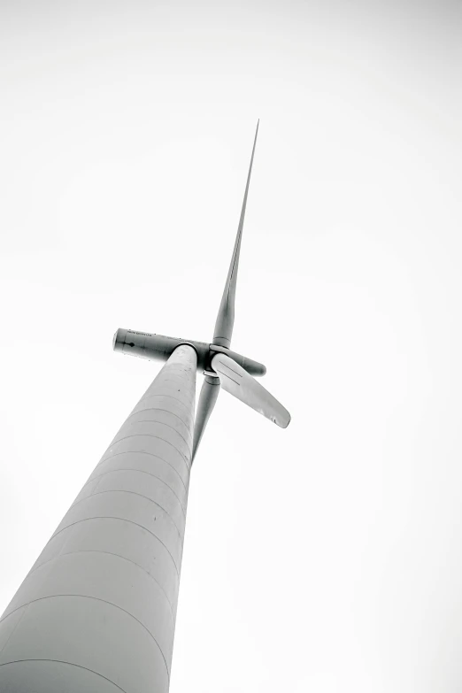 the view from below of a white tower with wind turbine