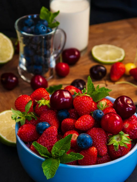 a blue bowl filled with berries and limes