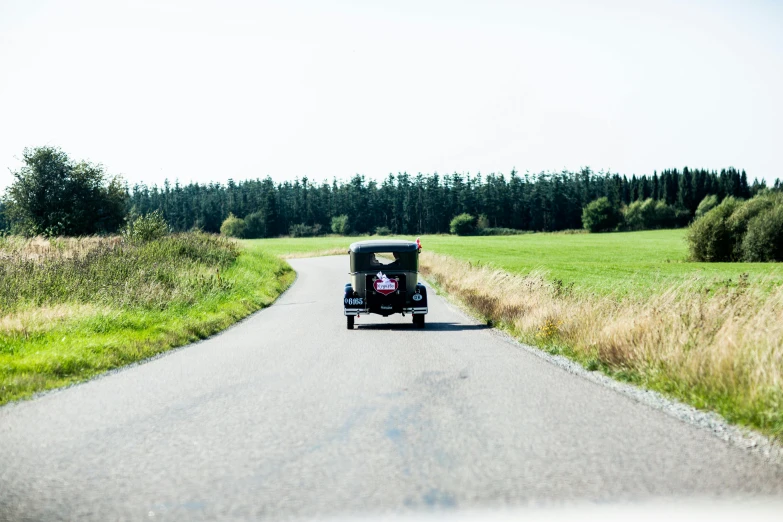 a black car driving down a rural road