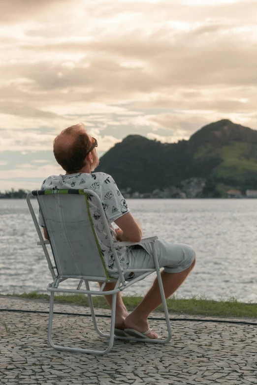 a person sitting on a beach chair looking out over the water