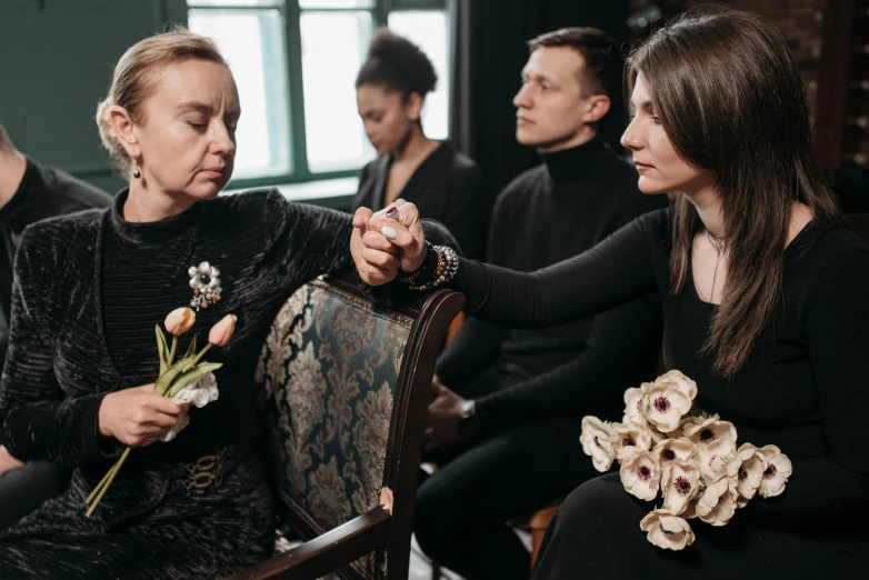 a women who is holding some flowers and touching another woman's face