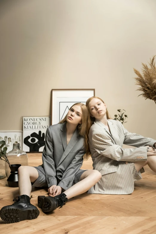 two young women sitting on a floor in business attire