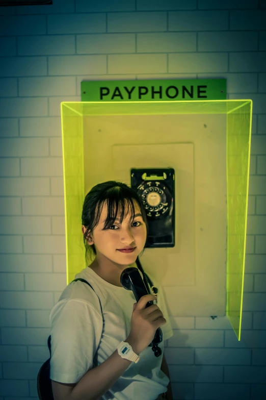 a woman holds a phone and stands next to a sign