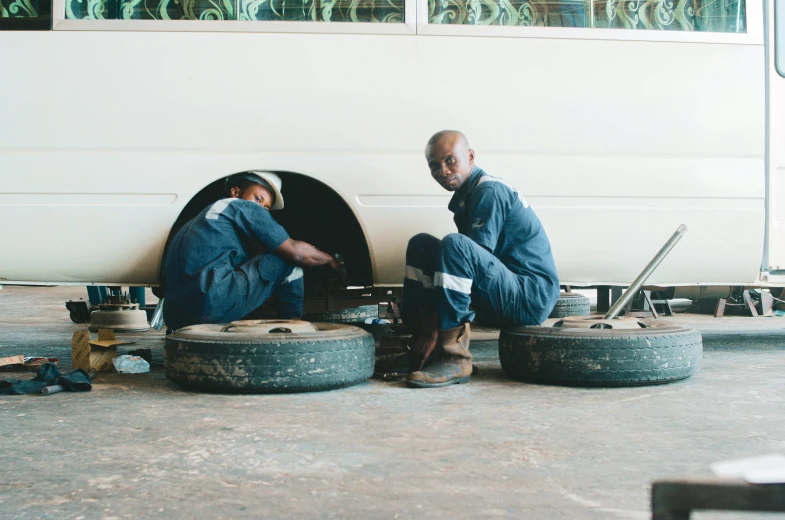 two men are sitting down in front of some tires