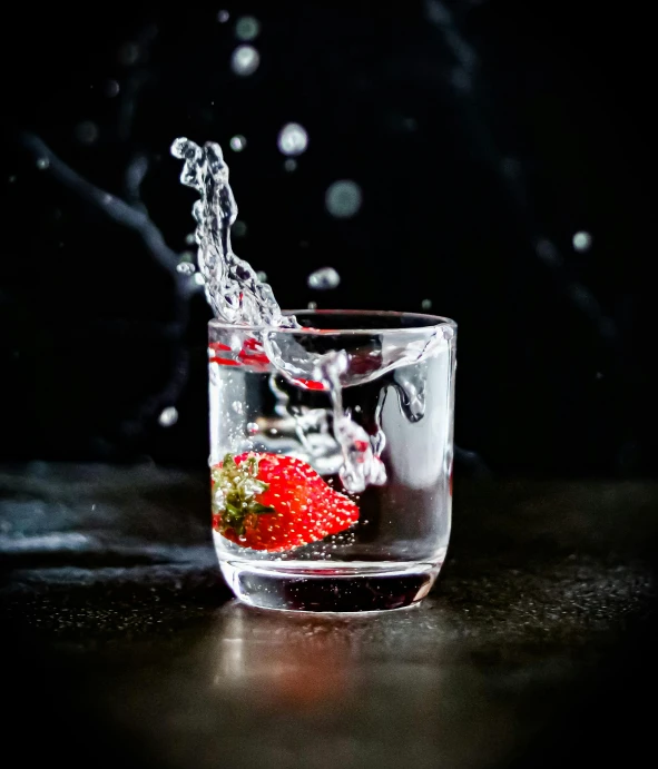 a glass filled with some water and a strawberry