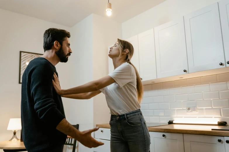 a young woman being playful with another male in the kitchen