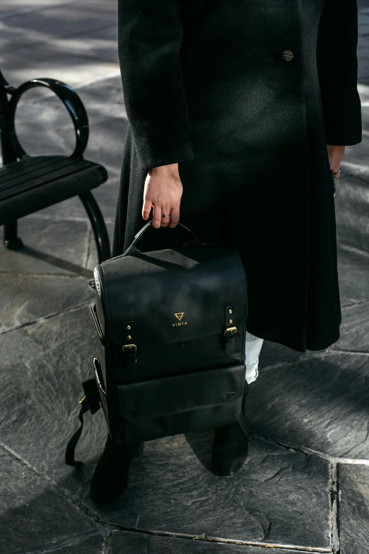 the person holds a black suitcase with two handles