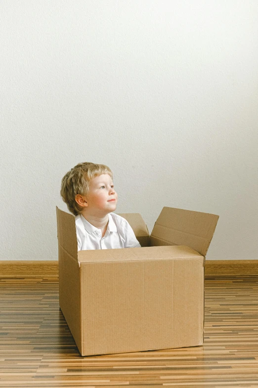 a boy is looking up in a moving cardboard box